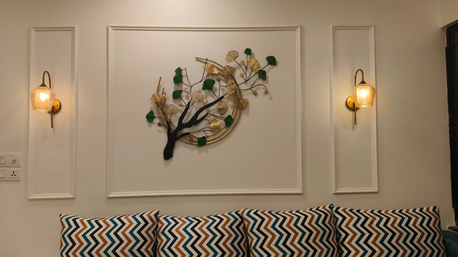 Accent wall with moulding panels and brass sconces by Artmarque, Pune